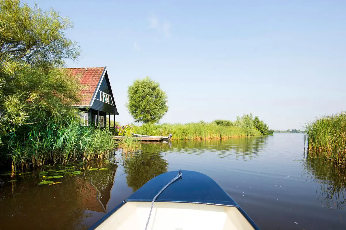 Met een sloep over het water van de Alde Feanen, met een huisje aan de waterkant