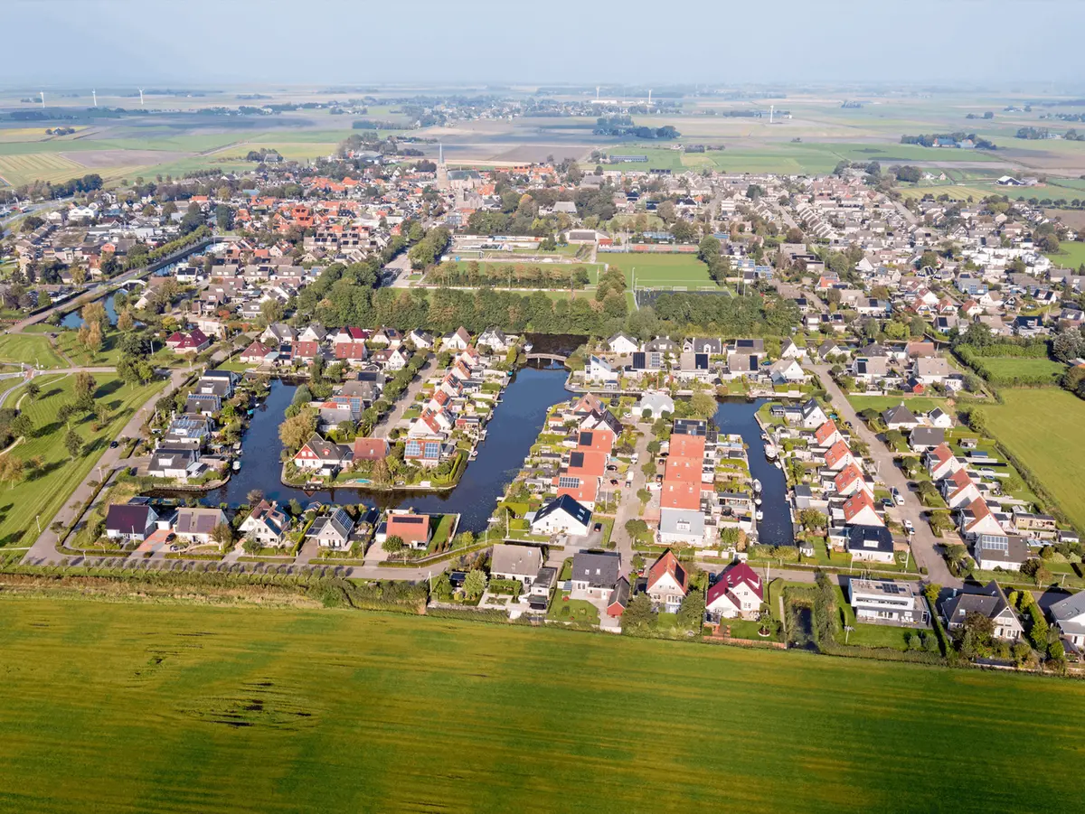 Luchtfoto van een woonwijk met vaarten en tuinen aan het water