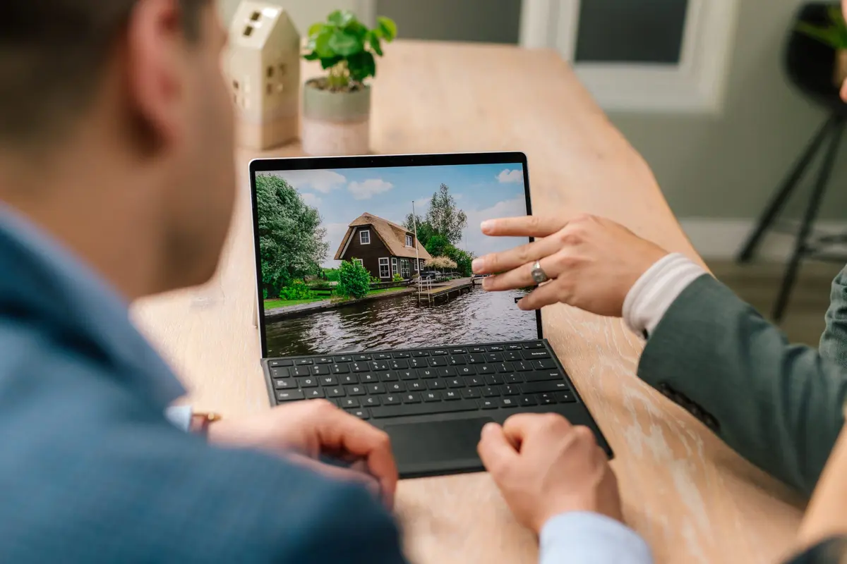Makelaar laat een klant een woning zien op een tablet
